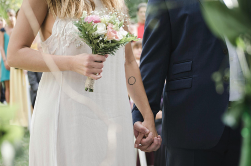 A bride and groom walking down the aisle, featuring a close-up of the wedding bouquet.